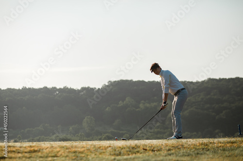 Golfers in a ready position plays swing shot on teeing ground in warm sunshine. leisure and sport concept.