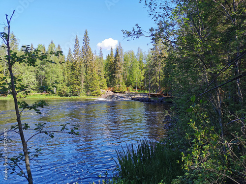 A picturesque waterfall on the Tokhmayoki River in Karelia surrounded by trees on a clear summer morning. photo