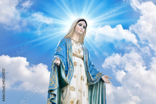 Photo Statue of Our lady of grace virgin Mary with Bright Blue Sky and beautiful clouds with abstract colored background and wallpaper at Thailand