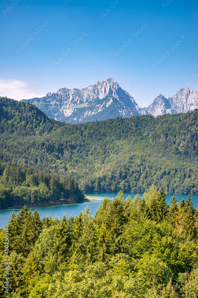 Blue Alpsee Lake in the Green Forest and Beautiful Alps Mountains in the Morning Fog. Fussen, Bavaria, Germany
