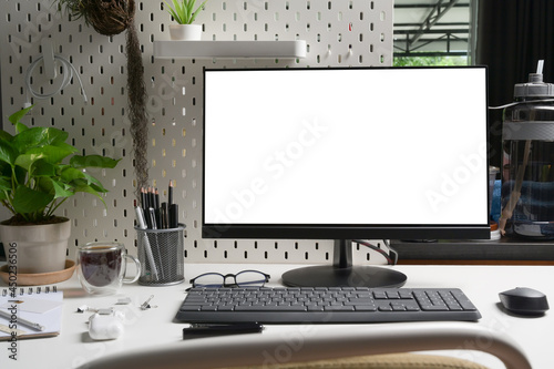 Mock up computer with white screen on office desk.
