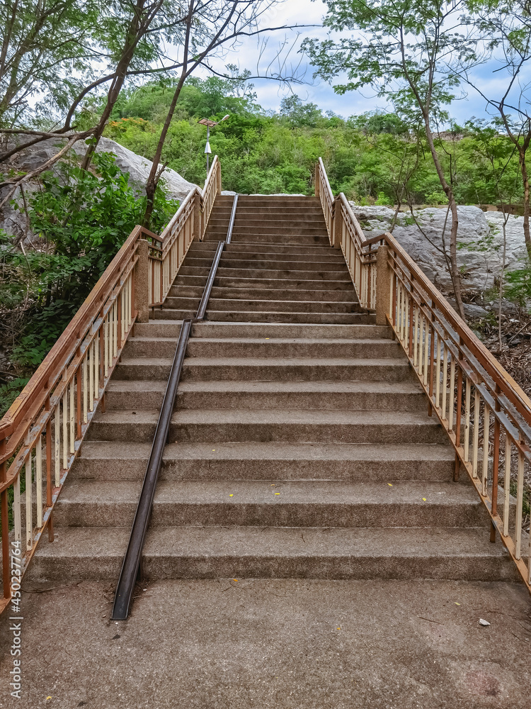 Obraz premium Stair-safe bike ramp along stairs. Comfortable and safe lanes for bicycles on stairs. Old and rusted steel rails for bicycles up and down for comfort between steps on stairs in the public park.