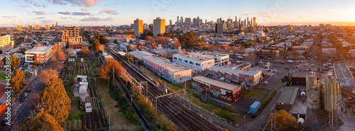 Aerial panoramic view of a busy city suburb at sunset with a railway line running through it photo