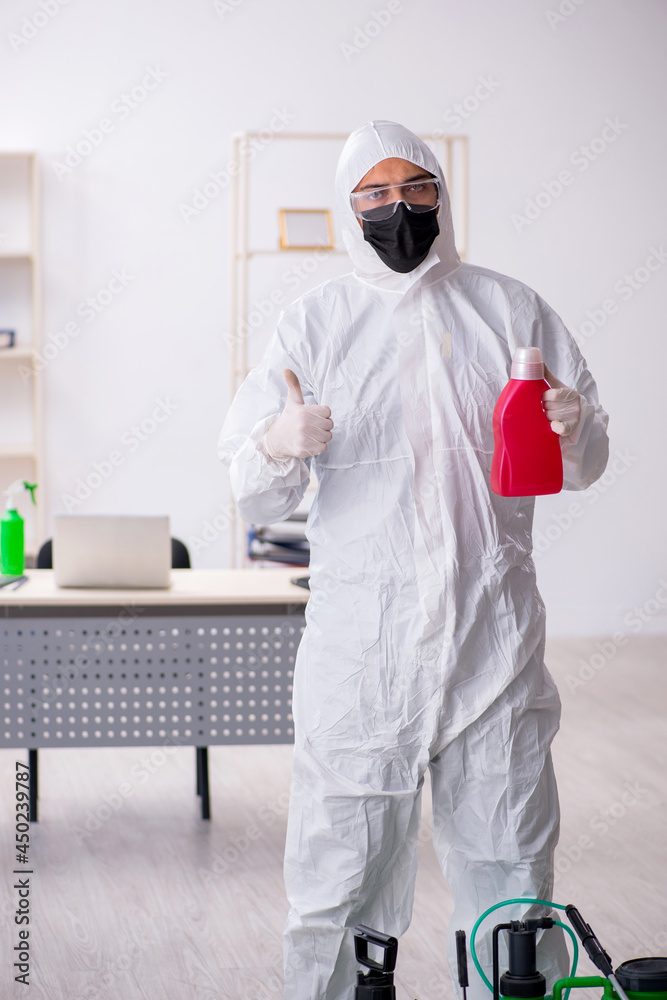 Fototapeta premium Young male contractor disinfecting office during pandemic