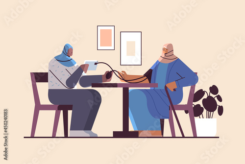 arab nurse or volunteer checking blood pressure to elderly arabic woman patient home care services healthcare