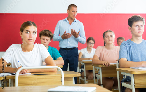 Pupils sitting in class and listening carefully to male teacher.
