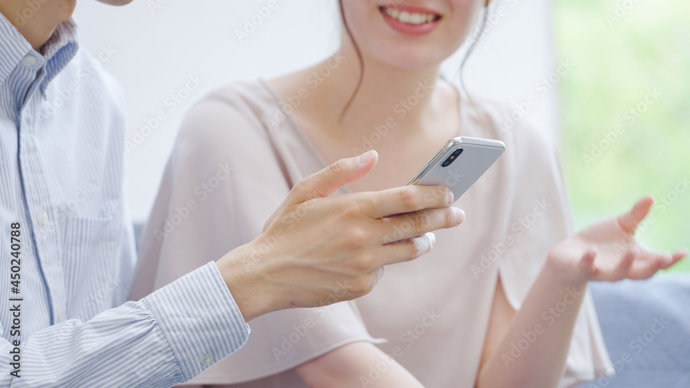 スマホを見る若い夫婦・カップル スマホを見る若い夫婦・カップル