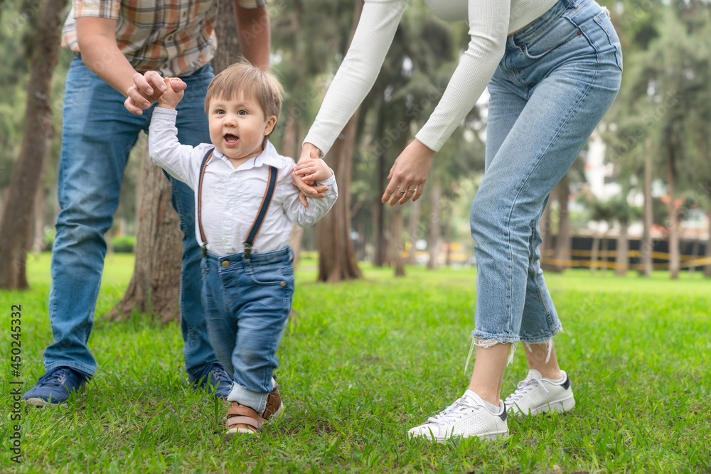 Fototapeta premium Parents helping a child to walk outdoors