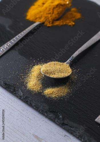 dried garlic on a spoon on a black plate.