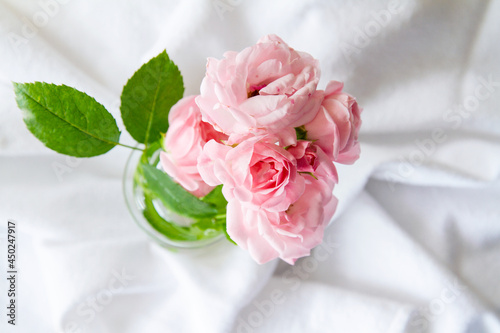 View from directly above of small bouquet of roses in a glass vase  Bouquet of pink roses on a crumpled cloth