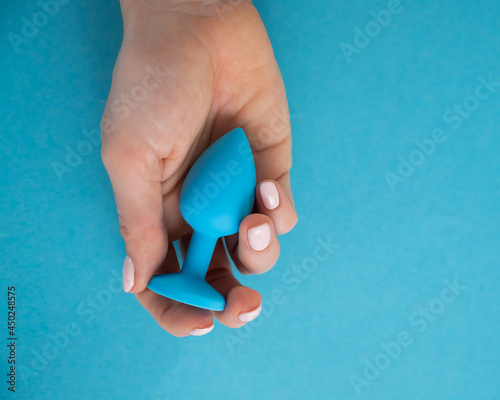 Obraz na plátně A woman is holding a blue anal plug on a blue background