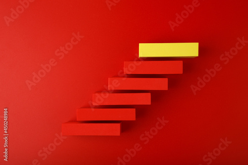 Modern and trendy business, personal development or scoring a goal concept. Top view of ladder made of red and yellow blocks on red background