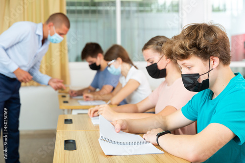 Portrait of teenager in protective face mask writing in workbook on lesson. New life reality during COVID pandemic