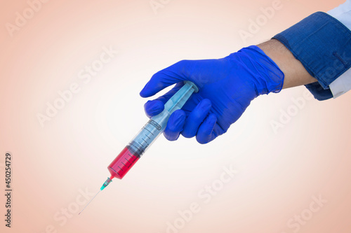 Conceptual image of a gloved hand holding a syringe