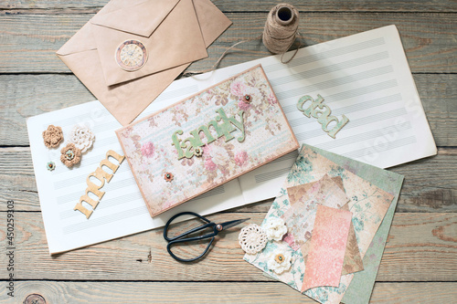 Scrapbooking. On a wooden background, a girl makes a photo album for a family in a vintage style.