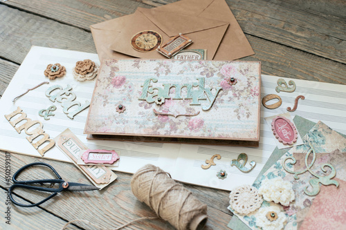 Scrapbooking. On a wooden background, a girl makes a photo album for a family in a vintage style.