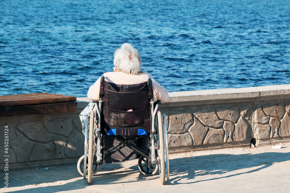 Fototapeta premium Lonely elder senior woman in wheelchair watch the sea