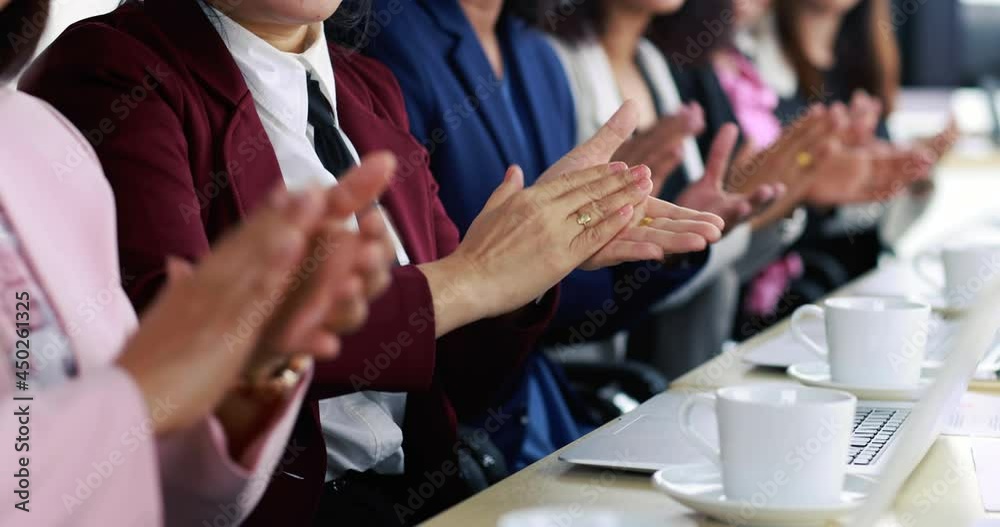 Group of businesswomen in suit sitting at working desk and clapping hands for appreciating to someone in modern office company. Concept of good circumstance in company with friends and colleagues.