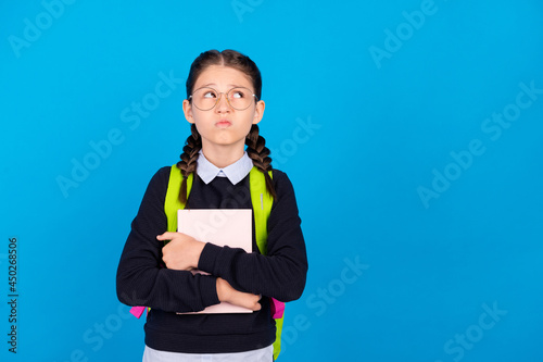 Photo of unhappy upset negative mood look copyspace grimace hold book wear backpack isolated on blue color background