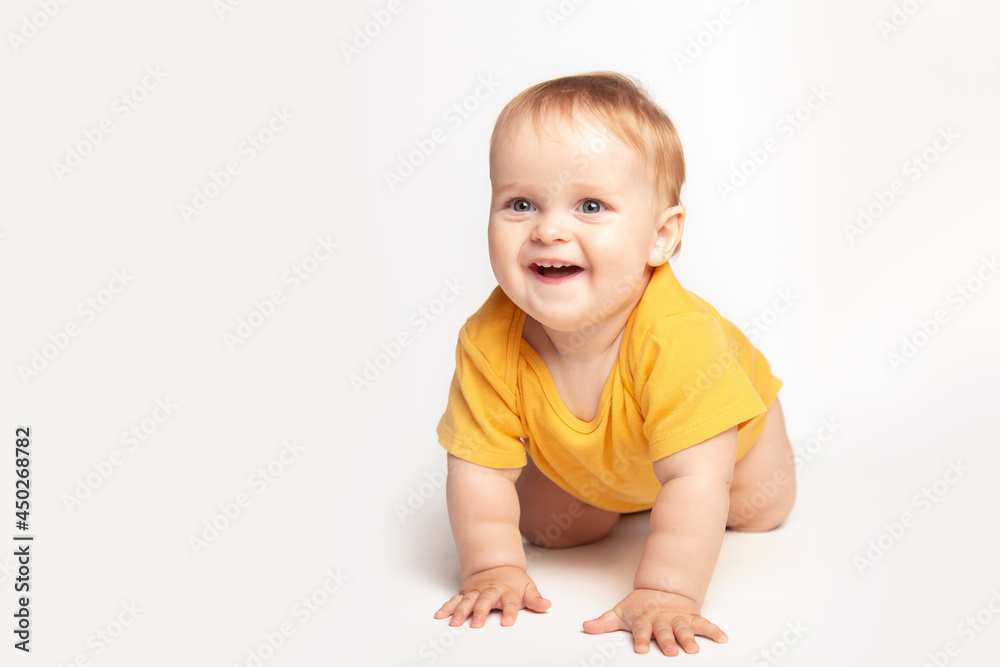 Cute small caucasian toddler baby boy child crawl on white studio floor. Smiling little infant kid wearing a yellow t-shirt explore world. Childcare and upbringing concept. Cute small caucasian toddler baby boy child crawl on white studio floor. Smiling little infant kid wearing a yellow t-shirt explore world. Childcare and upbringing concept.