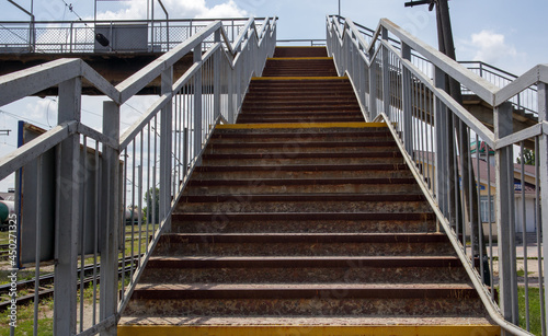 Railway bridge with steps, with impressive steps in perspective. Overhead pedestrian crossing. Bridge stairs connecting one platform to another at the train station.