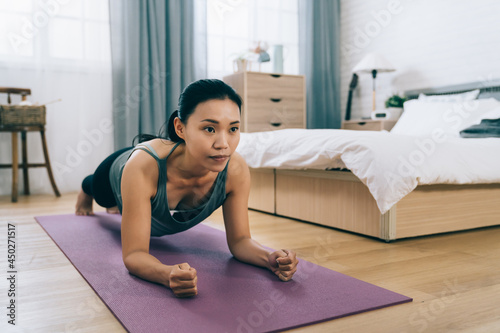 closeup view fit asian female is practicing plank on yoga mat. taiwanese woman doing ab exercise holding up her body with both forearms. workout and healthy lifestyle concept