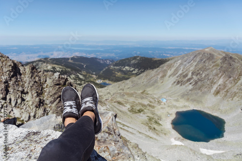 Legs with Hiking Sneakers of Woman Sitting on a High Mountain Top with Lake View.Rila Mountain ,Musala Peak 