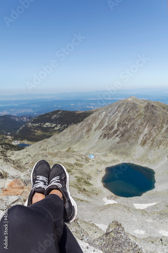 Legs with Hiking Sneakers  of Woman  Sitting on a High Mountain Top with Lake View.Rila Mountain ,Musala Peak  © boryanam