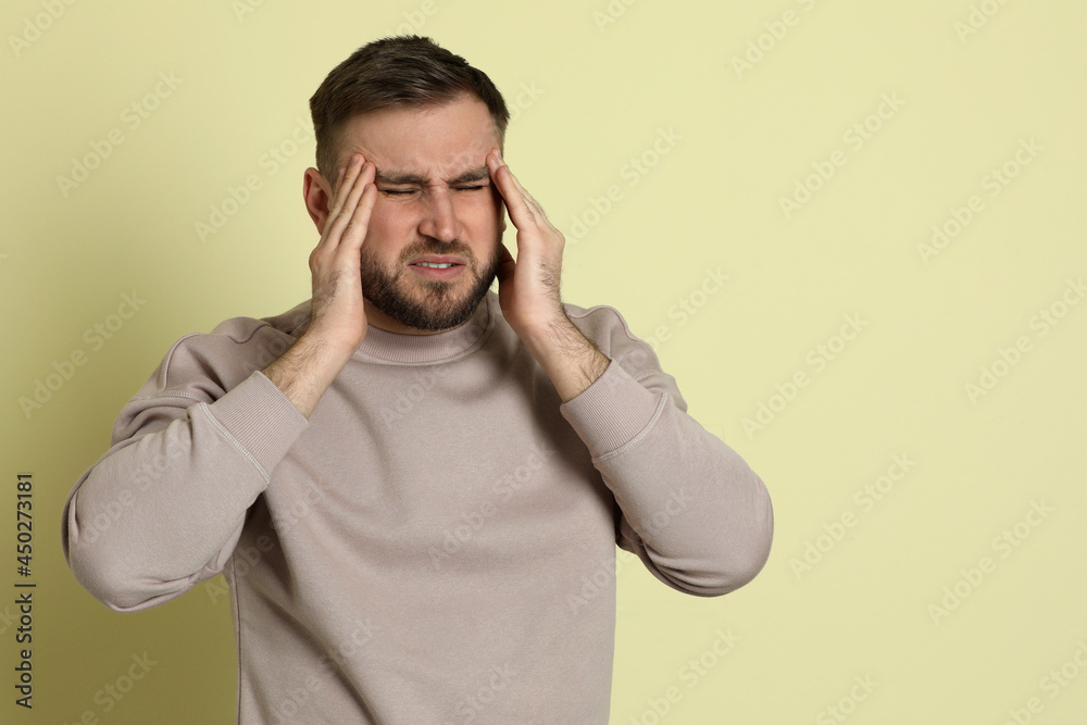 Man suffering from migraine on light green background. Space for text Man suffering from migraine on light green background. Space for text