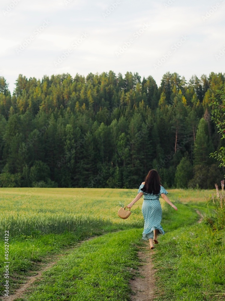 Happy girl running barefoot on the road in a wheat field. Rear view. Nature beauty, blue sky, field wheat. Freedom, Sustainable lifestyle, Wellness Happy girl running barefoot on the road in a wheat field. Rear view. Nature beauty, blue sky, field wheat. Freedom, Sustainable lifestyle, Wellness