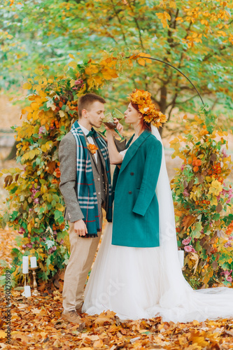 Wedding ceremony in the autumn park. The newlyweds standing near the decorated arch.