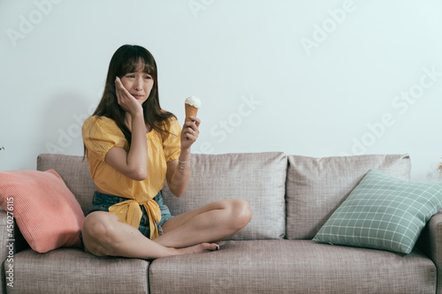 фотографія asian girl experiencing sudden sharp pain when eating ice cream