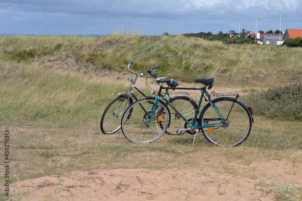 Deux vélos sur béquilles dans les dunes proches de la plage.