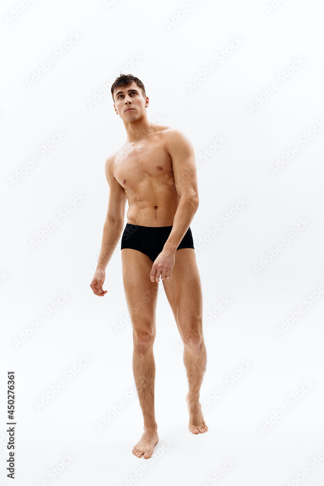 male bodybuilder with a pumped-up muscular body dark in shorts light isolated background
