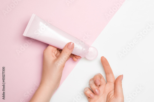 Cosmetic face mask on a light background, female hands squeeze the contents onto the finger.