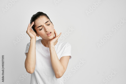 Woman in white t-shirt holding her head dissatisfied with health problems