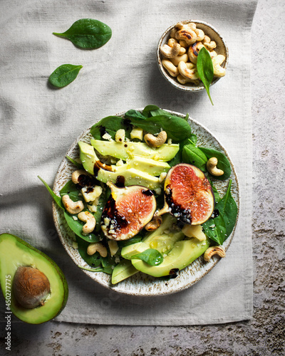 Salad with figs, avocado, spinach and cashews. Dressing from balsamic sauce. Food styling of a vegetarian salad. Organic food. Green salad with avocado and nuts