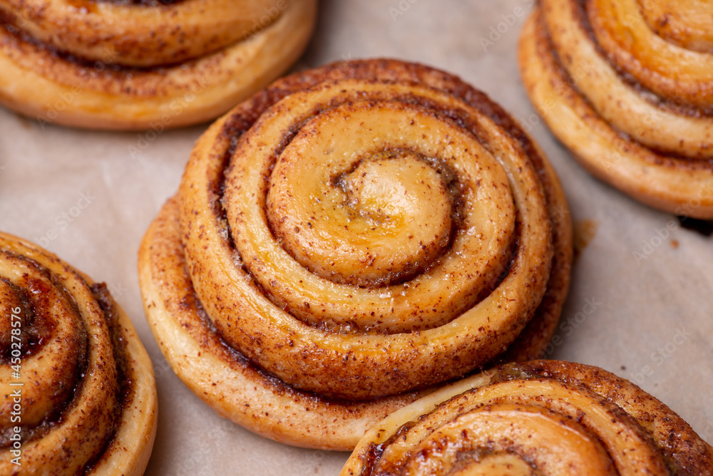 Many fresh baked buns with cinnamon on baking paper. Cooking tasty bakery at home Many fresh baked buns with cinnamon on baking paper. Cooking tasty bakery at home