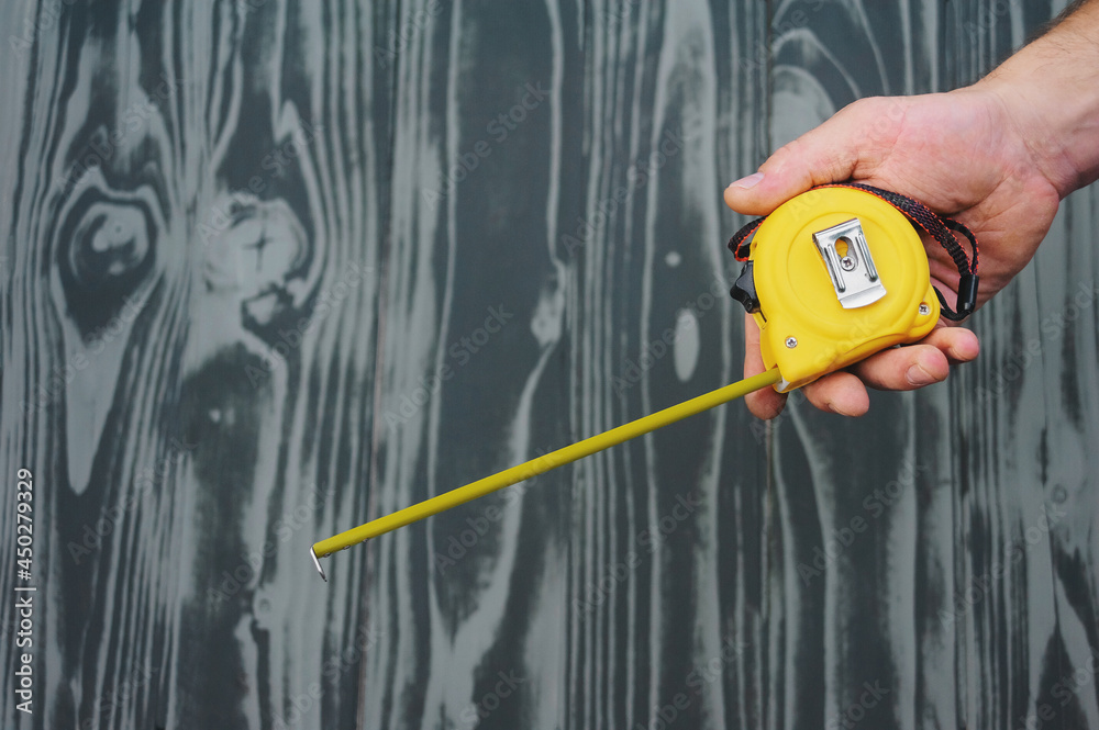 construction tape in hand on gray wooden texture background