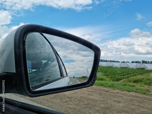 side mirror. shooting from passenger seat. travel along the road along fields. 