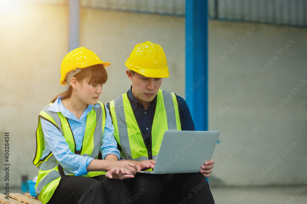 Team engineers and foreman wear a mask, hard hat, and vest. Standing consult discuss industrial production management. Explaining job details through laptops and tablets in factories or warehouses. Team engineers and foreman wear a mask, hard hat, and vest. Standing consult discuss industrial production management. Explaining job details through laptops and tablets in factories or warehouses.