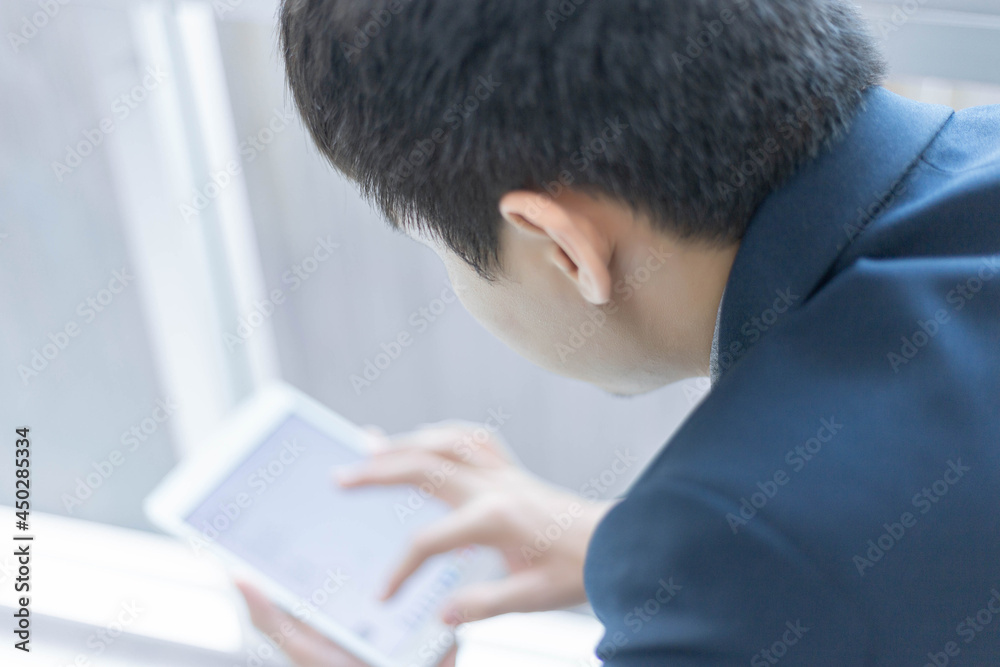 Business partners concept a young businessman wearing navy suit jacket looking on the tablet screen checking an email inbox
