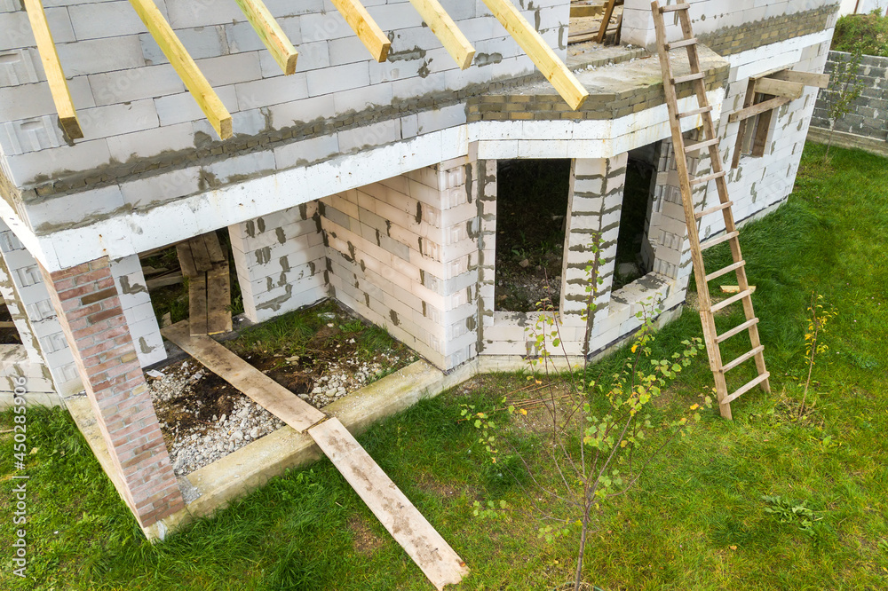 Aerial view of a private house with aerated concrete brick walls and wooden frame for future roof.