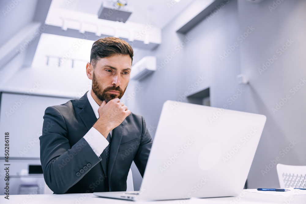 Portrait of a young man sitting at his desk in the office workin Portrait of a young man sitting at his desk in the office workin