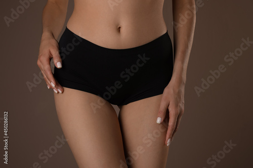 Slim woman with smooth skin in underwear on beige background, closeup. Cellulite problem concept