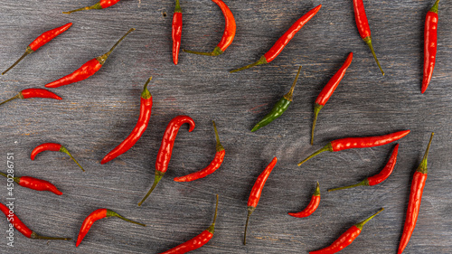 Small pods of hot chili peppers on a wooden surface, top view, pattern