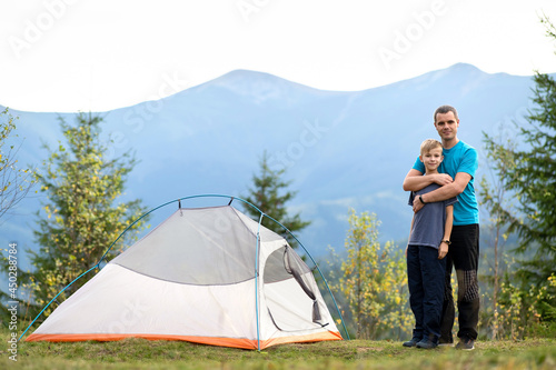 Young dad and his child son hiking together in summer mountains. Active family travelling concept.
