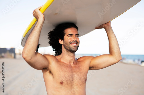 Surfer with his surfboard. Young handsome man with a surfboard on the beach