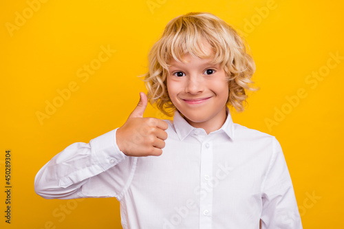 Photo of cheerful schoolboy raise thumb up agree solution wear school uniform isolated yellow color background