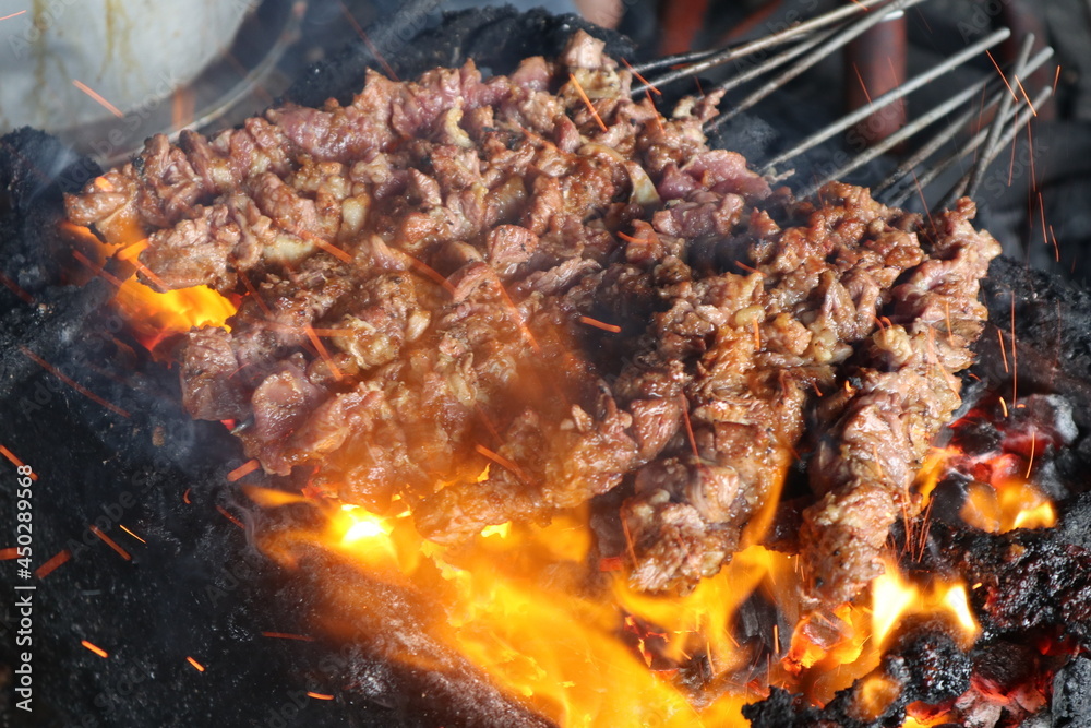 sate kambing or satay goat, lamb, Lamb or meat goat satay with charcoal  ingredient on red fire grilling by people. traditional satay from yogyakarta, java, Indonesia 

cooking satay